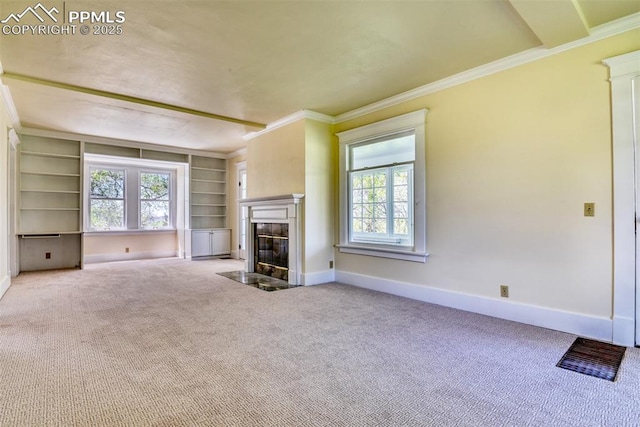 unfurnished living room with built in features, crown molding, carpet flooring, baseboards, and a fireplace with flush hearth