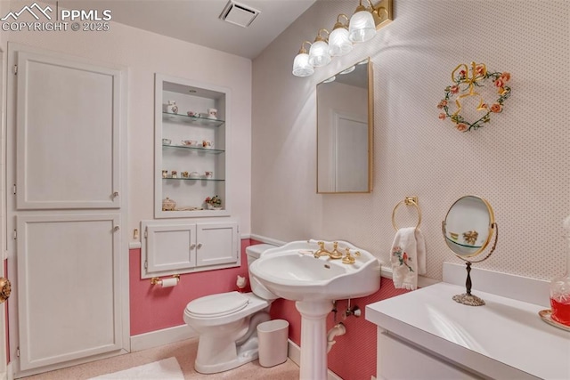 bathroom featuring a sink, toilet, visible vents, built in features, and baseboards