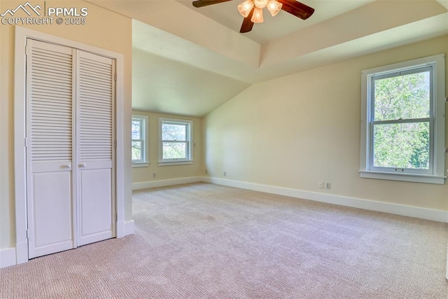 unfurnished bedroom featuring light colored carpet, a closet, baseboards, and lofted ceiling