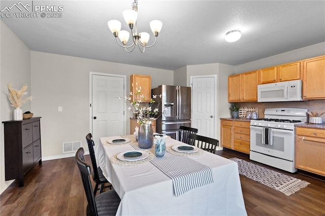kitchen with white appliances, visible vents, an inviting chandelier, and dark wood finished floors