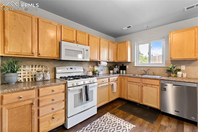kitchen with visible vents, light brown cabinets, white appliances, dark wood-style floors, and a sink
