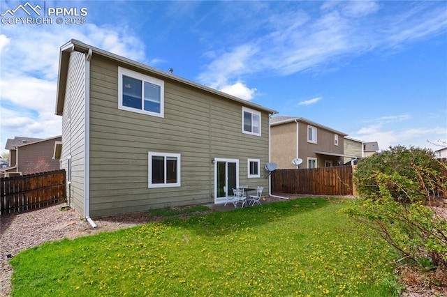 rear view of house with a fenced backyard and a lawn