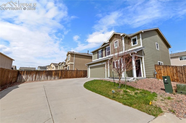 view of front of house featuring fence, concrete driveway, and a garage