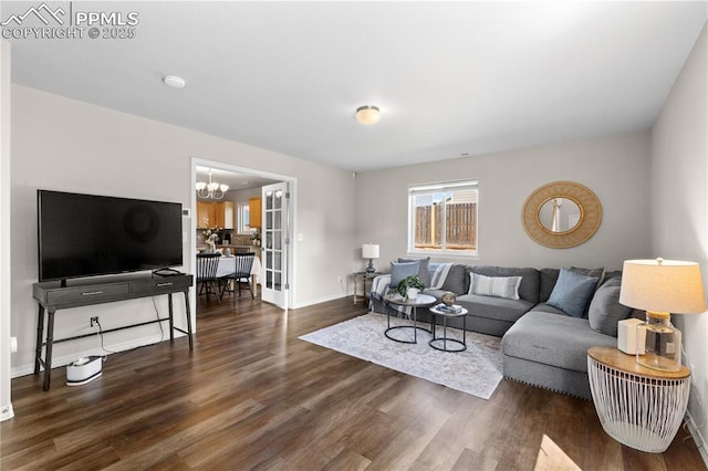 living area featuring baseboards, an inviting chandelier, and wood finished floors