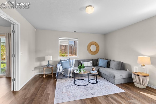 living area with plenty of natural light, baseboards, and dark wood-style floors