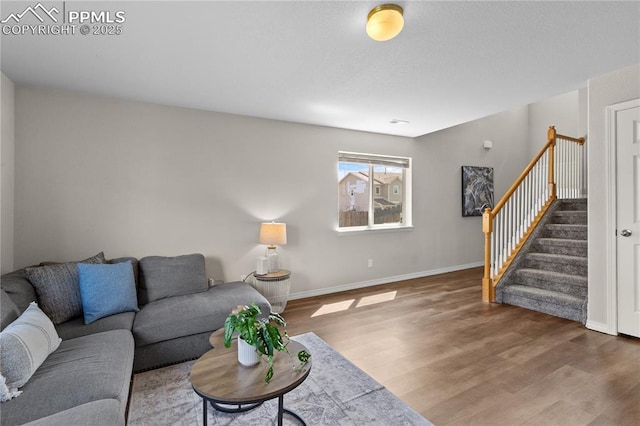 living room featuring stairs, baseboards, and wood finished floors
