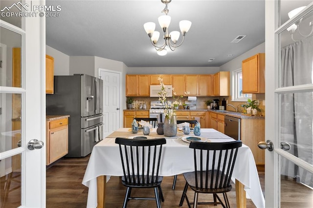 kitchen with dark wood-style flooring, a notable chandelier, appliances with stainless steel finishes, and a sink
