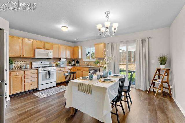 kitchen featuring light brown cabinetry, wood finished floors, light countertops, a notable chandelier, and white appliances
