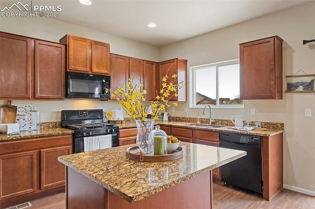 kitchen featuring light stone countertops, a sink, and black appliances