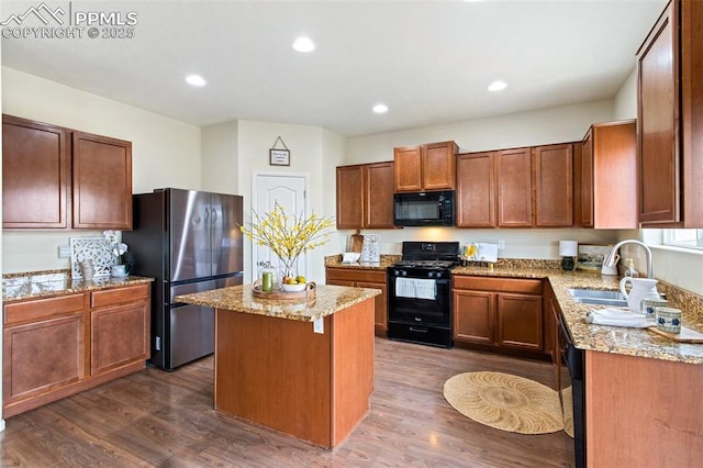 kitchen featuring light stone countertops, a sink, dark wood-type flooring, a kitchen island, and black appliances