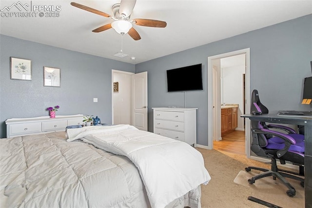 bedroom featuring ceiling fan, light colored carpet, and ensuite bath
