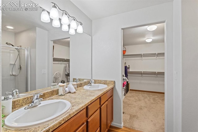 full bathroom with double vanity, a walk in closet, a sink, and a stall shower