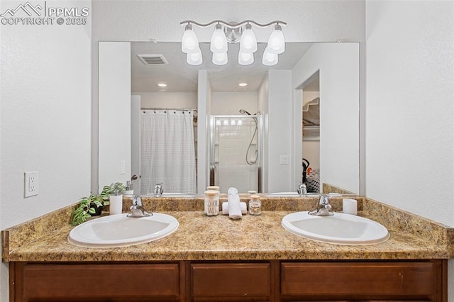 full bath with visible vents, a sink, a stall shower, and double vanity