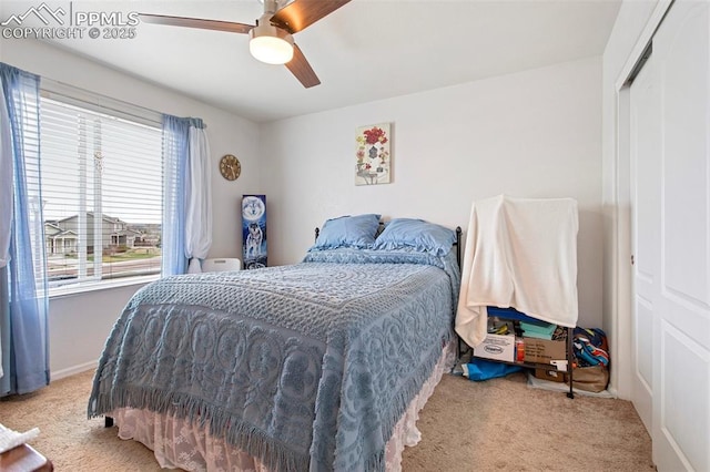 bedroom featuring ceiling fan, light carpet, multiple windows, and a closet