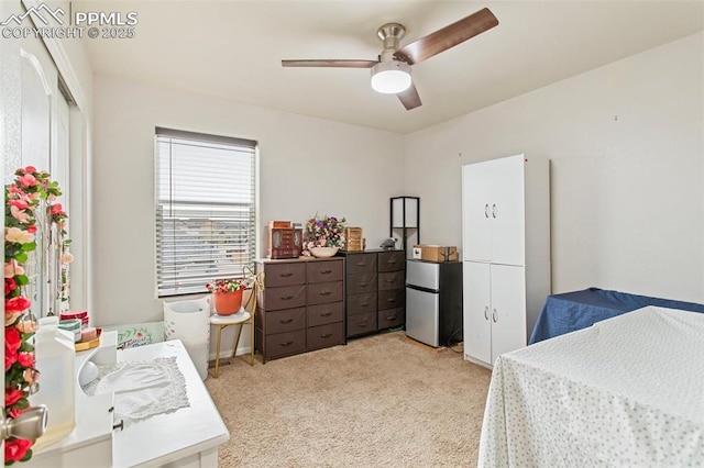 bedroom featuring freestanding refrigerator, a ceiling fan, and light colored carpet