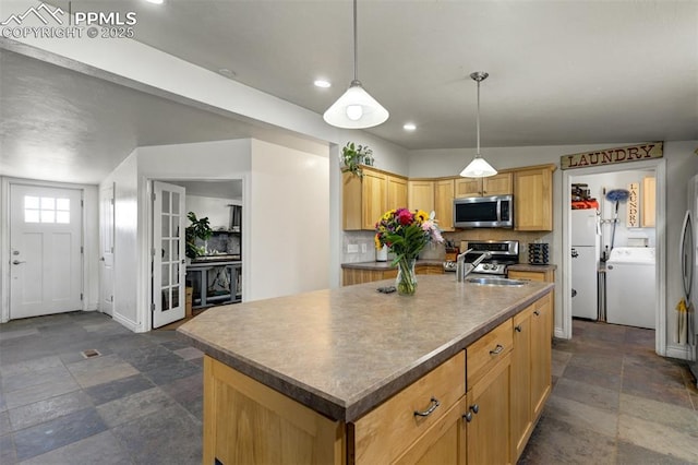 3235 S Meridian Rd, Colorado Springs, CO 80929 - kitchen featuring a kitchen island with sink, backsplash, stone finish flooring, washer / clothes dryer, and appliances with stainless steel finishes