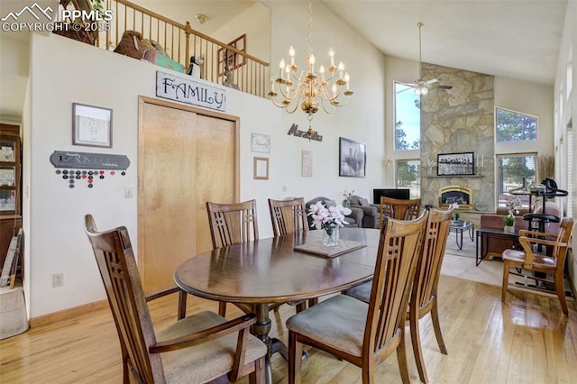 7850 Wilderness Dr, Colorado Springs, CO 80908 - dining area with high vaulted ceiling, light wood-style floors, ceiling fan, a stone fireplace, and a chandelier