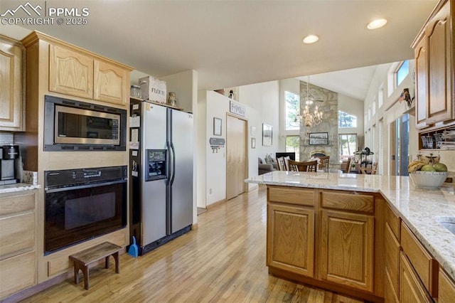 7850 Wilderness Dr, Colorado Springs, CO 80908 - kitchen featuring stainless steel appliances, light wood-type flooring, light stone countertops, a peninsula, and lofted ceiling