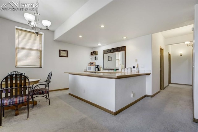 7850 Wilderness Dr, Colorado Springs, CO 80908 - kitchen with light carpet, baseboards, a chandelier, white microwave, and a peninsula