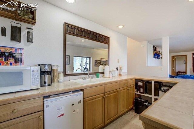 7850 Wilderness Dr, Colorado Springs, CO 80908 - kitchen featuring white microwave, a sink, refrigerator, tile counters, and recessed lighting