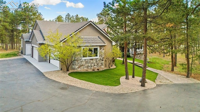 4415 Hidden Rock Rd, Colorado Springs, CO 80908 - view of front of home with stone siding, driveway, a front yard, a tile roof, and an attached garage