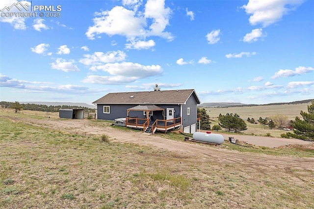 17880 Plains Edge Ct, Peyton, CO 80831 - rear view of house featuring a wooden deck, a shed, a rural view, a lawn, and an outdoor structure