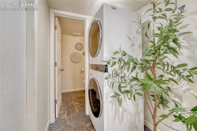26 Mountain View Rd, Manitou Springs, CO 80829 - laundry area featuring estacked washer and dryer, stone tile floors, and baseboards