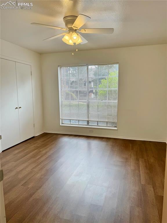 unfurnished bedroom with baseboards, a ceiling fan, a closet, and wood finished floors