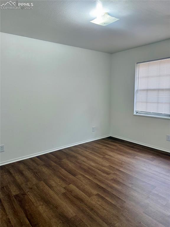 empty room featuring dark wood-style flooring and baseboards