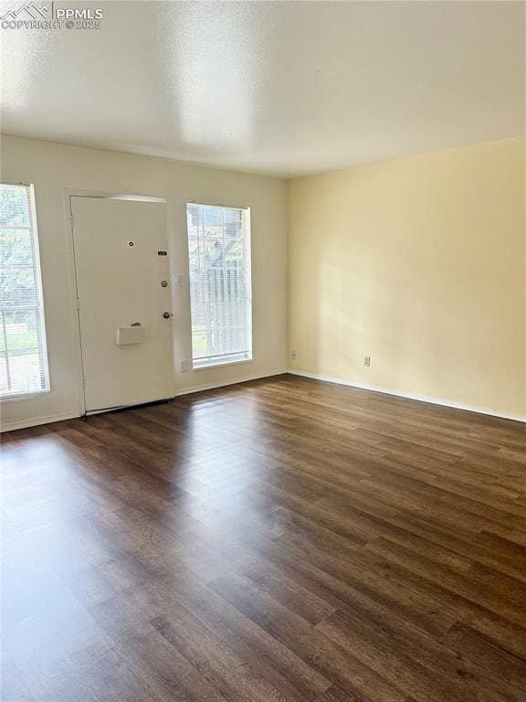 foyer with dark wood-type flooring and baseboards