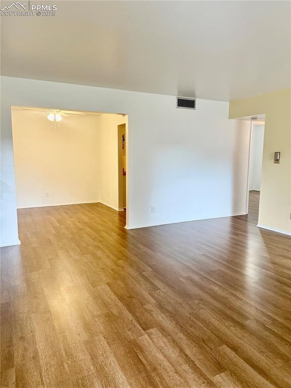 spare room with a ceiling fan, baseboards, visible vents, and wood finished floors