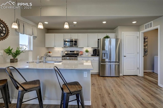 7352 Cornice Pt, Colorado Springs, CO 80923 - kitchen featuring visible vents, a peninsula, a breakfast bar, a sink, and appliances with stainless steel finishes