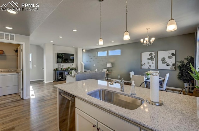 7352 Cornice Pt, Colorado Springs, CO 80923 - kitchen with stainless steel dishwasher, visible vents, washer / clothes dryer, white cabinets, and a sink