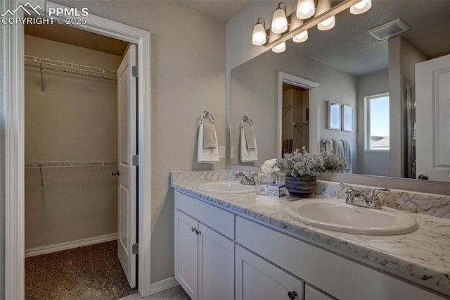 7352 Cornice Pt, Colorado Springs, CO 80923 - bathroom featuring double vanity, visible vents, a sink, and a spacious closet