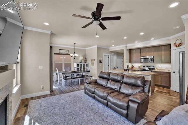 835 Redemption Pt, Colorado Springs, CO 80905 - living area with wood finished floors, ceiling fan with notable chandelier, baseboards, ornamental molding, and recessed lighting