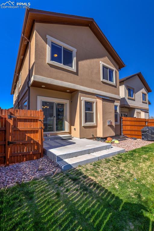 835 Redemption Pt, Colorado Springs, CO 80905 - rear view of property with a fenced backyard, a patio, stucco siding, and a lawn