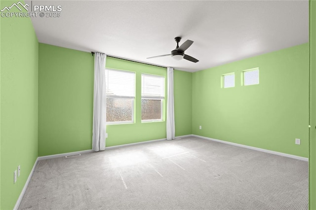 carpeted spare room with baseboards and a ceiling fan