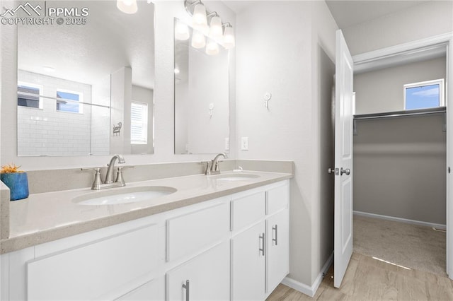 full bath with double vanity, a healthy amount of sunlight, and a sink