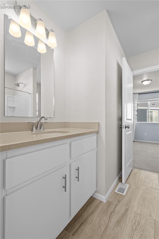 bathroom featuring vanity, baseboards, visible vents, and a shower