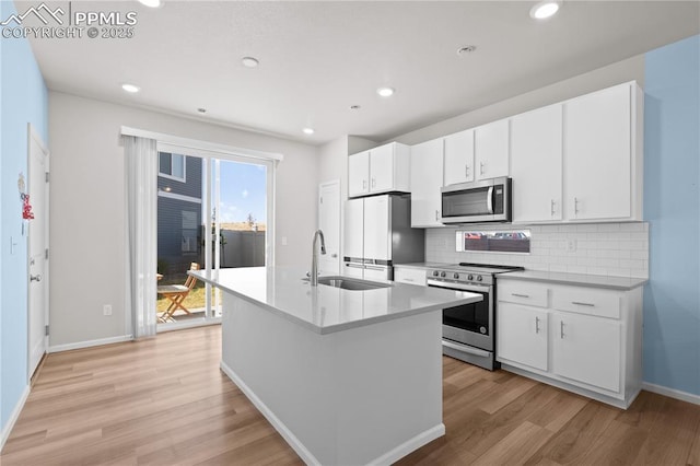 kitchen with a sink, tasteful backsplash, light wood finished floors, baseboards, and appliances with stainless steel finishes