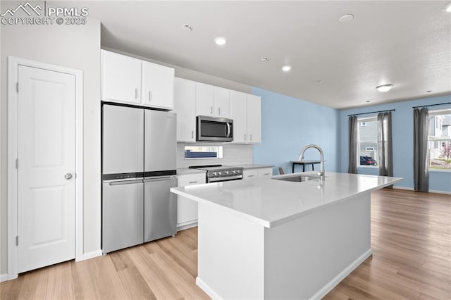 kitchen with a sink, white cabinetry, light wood-style floors, and appliances with stainless steel finishes