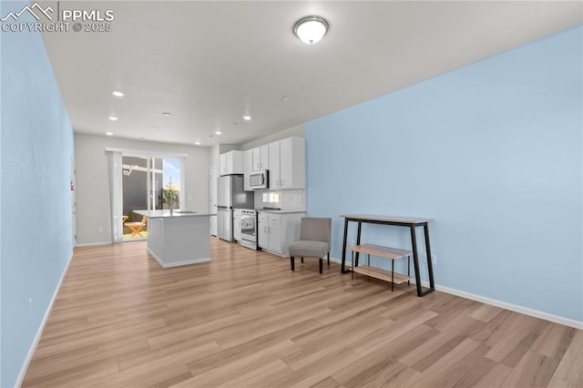 living area with baseboards, light wood-style floors, and recessed lighting