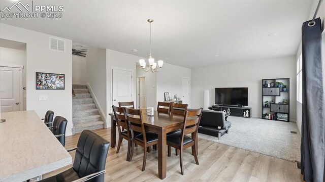 6555 Roundtail Way, Colorado Springs, CO 80925 - dining space featuring an inviting chandelier, stairs, light wood-style flooring, and visible vents