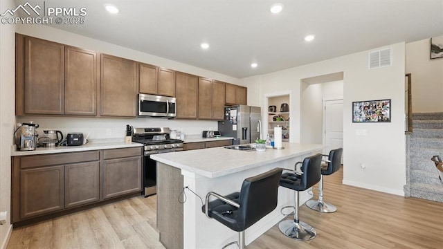 6555 Roundtail Way, Colorado Springs, CO 80925 - kitchen featuring light wood finished floors, a kitchen bar, stainless steel appliances, and visible vents