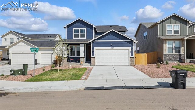 6555 Roundtail Way, Colorado Springs, CO 80925 - craftsman house featuring board and batten siding, fence, a garage, concrete driveway, and stone siding