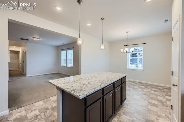 kitchen featuring baseboards, a chandelier, light stone counters, a center island, and recessed lighting