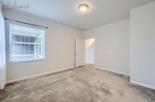 unfurnished room featuring carpet and baseboards