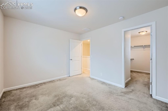 unfurnished bedroom featuring carpet floors, a walk in closet, and baseboards