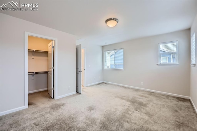 unfurnished bedroom with carpet floors, a walk in closet, and baseboards