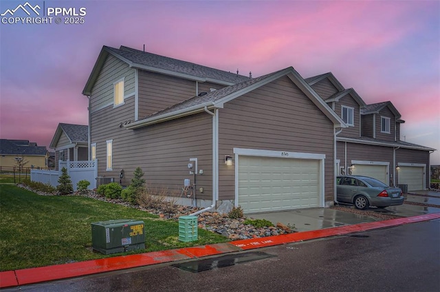 property exterior at dusk featuring concrete driveway, central AC, and a garage